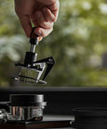 Image of 58mm Espresso Needle Distributor Features Nine Fine Thin Needles Adjustable Height Frame and Sleek Black Cleaning Base in use.