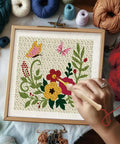 Close-up of hand using punch needle on framed cloth from Two Pack Flower Butterfly Punch Needle Kit Set With Frames For Beginners, Includes 12 Yarn Colors, Hook, Pattern And Instructions, Ideal Starter Embroidery Kit For Wall Hanging 9.4 By 9.4 Inches
