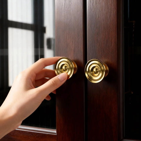 Hand reaching for 4 Pack Solid Brass Gold Sunburst Cabinet Knobs 1.65 Inch Oversized Round Drawer Pulls on wooden cabinet