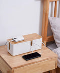 Cable Management Box With Bamboo Lid For Hiding Extension Cords And White Surge Protectors on a nightstand, tidy space