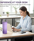 Portable Breast Milk Cooler Bottle With Touch Temp Display And Color Coded Safety Alert For Travel on a desk next to a woman working.