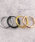 Four hoop earrings in different finishes; black titanium, gold, silver, and rose gold on stone surface, with one Black Titanium Hoop Earrings 2.5x10mm For Women And Men, Simple Circle Hoops, Hypoallergenic Durable Jewelry With Polished Inner Face, Comfortable Everyday Wear, Long Color Retention, Sleek Minimalist Design.
