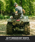 12 Volt ATV UTV Broadcast Spreader With Rain Cover 80 LB Capacity Front Or Back Mount on ATV in forest spreading seeds