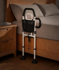 Easy Access Bed Rail For Seniors With No Slip Ergonomic Handle And Storage Pocket beside a wooden bed.