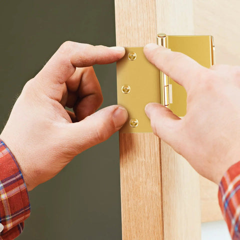 Hands installing brass expandable door hinges with offset design adds two inches to door openings for wheelchairs walkers.