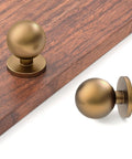 30 Pack 1 Inch Round Solid Ball Cabinet Knobs In Rich Champagne Bronze Finish on wooden surface, showcasing modern design and tight fit.
