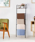 Versatile Blanket And Towel Ladder With Shelf Wall Leaning Black Iron Rack For Living Room Or Bathroom Cozy Space Saver Home Decor Rustproof Finish For Easy Access In Laundry Or Bath Organization, displaying throws and decor.