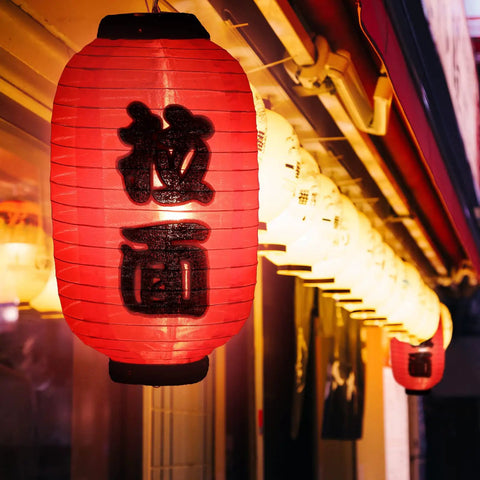 Japanese Style Red Silk Lanterns 14 Inch Traditional Hanging Lamps Waterproof Indoor Outdoor Festival Decor Izakaya Tavern Vibe Reusable Set Of 4 For Home Yard Patio Bar Parties hanging outside a building illuminated by warm light.