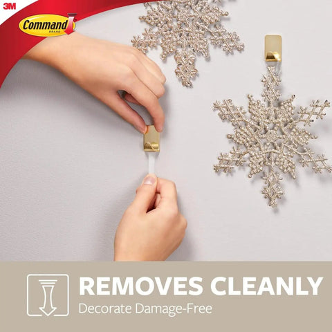 Person using Small Brass Tone Metal Hooks With Adhesive Strips, 4 Hooks And 5 Strips, Damage Free Wall Hangers, No Tools Needed