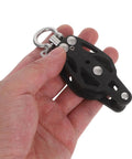 Close-up of a hand holding a black Nylon Pulley Wheel Single Bearing Block for Marine Use Durable Black Resistance Pulley