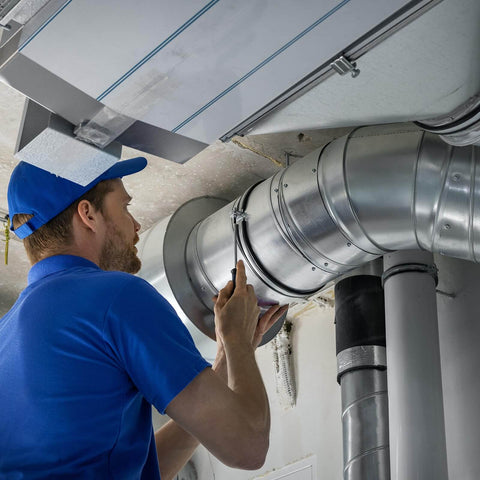 Technician adjusting ventilation duct in industrial setting.