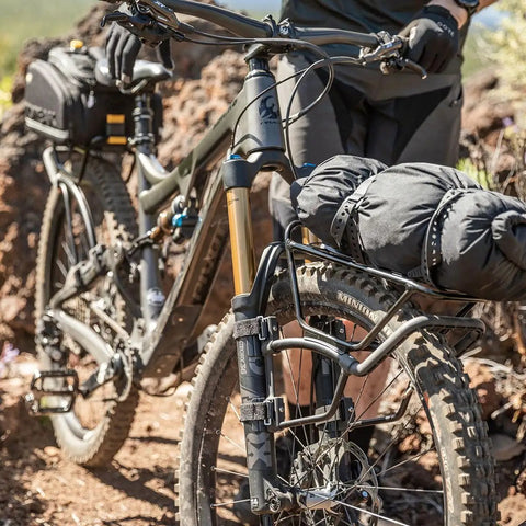 Mountain bike equipped with TetraRack M1 Fork Mount Rack For Bikes, Adjustable Top Plate Keeps Loads Level, and strapped gear.
