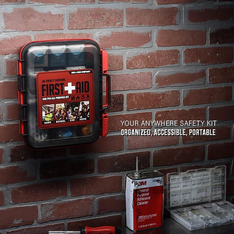 Front view of red-and-black portable first aid kit case with 400-pcs label mounted on brick wall.