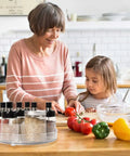Clear 11 Inch Lazy Susan Organizer With Five Removable Bins on kitchen counter with spices, next to woman and child cooking.