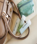 Compact White Label Maker Bundle With Four Tape Rolls For Hassle Free Home And Office Storage Featuring Dead Simple One Touch Keys Quick Print Templates And No Sweat Setup Design For Everyday Clutter Solutions Just Great resting beside a tan handbag and green pouch.