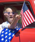 Child holding 8x12 Inch American Flag On Stick from 12 Pack With 17.5 Inch Wooden Poles during parade, showing vivid color.