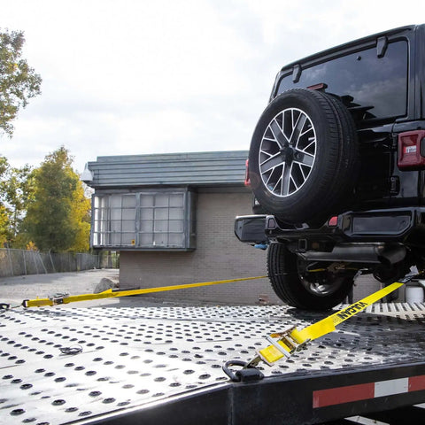 Complete Axle Strap Tie Down Kit With Snap Hook Ratchet Straps In Classic Yellow securing a vehicle on a trailer