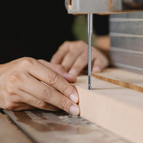 Drilling with Four Piece Quarter Inch Spade Drill Bit Extension Set, hands guiding wood under drill bit, woodworking project