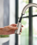 Top Shelf Stainless Steel Pull Down Kitchen Faucet Featuring One Handle High Arc Design With Fast Wash Power Boost And Smudge Resistant Matte Finish For Quick Cleanup And No Hassle Setup Plus Smooth Retractable Spray Hose Operation in hand.