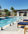 Heavy Duty Six Panel Frameless Tempered Glass Deck Railing Kit With Complete 2205 Stainless Steel Mounting Hardware 315 To 321 Inch Wide By 44 Inch Tall next to a poolside relaxation area.