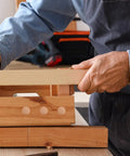 Person installing wooden furniture hole plugs for table and chair legs, round hardwood screw hole covers with snap fit easy install.