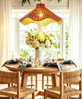 YUJIDAO 19.7 Inch Rattan Chandelier above a dining table, featuring boho design, hand-woven material, and flowers.