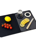 Black folding bar mat with cutting board; left ribbed drying surface with lemon and tomatoes, right with lemon slices.