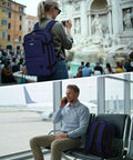 Go To Underseat Personal Item Travel Backpack With 10 Pockets And 180 Degree Opening 15.6 Inch Laptop Carry On Bag For Men And Women Navy Blue Fits United Airlines Cabin Size in city and airport scene.
