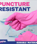 Person wearing hot pink nitrile exam gloves holding a sharp object to demonstrate puncture resistance and durability.