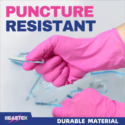 Person wearing hot pink nitrile exam gloves holding a sharp object to demonstrate puncture resistance and durability.