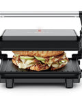 Chefman Indoor Grill Panini Press With Stainless Steel Finish And Nonstick Plates, grilling a thick sandwich filled with cheese.