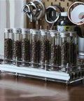 Single Dose Coffee Bean Storage Jars 14 Piece Glass Canisters With One Way Valve And Sturdy Metal Dispenser Stand displaying coffee beans in glass tubes.