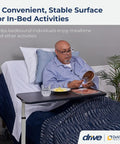 Heavy Duty Adjustable Overbed Table With Dead Simple Height Changes Non Tilt Wood Grain Top And Smooth Rolling Swivel Casters For Zero Hassle Room Moves in use beside a bed with a man eating.