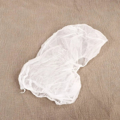 10 Pcs Disposable Nonwoven Bouffant Hair Caps With Straight Comfort Elastic Fit For Full Head And Face Shield White protective hat on brown fabric