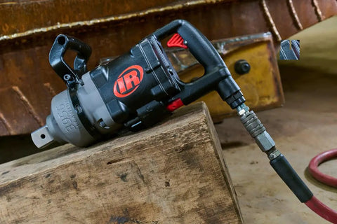 Badass 1 1/2 Inch Air Impact Wrench Blasts Through Frozen Lug Nuts With 7300 Nm Breakaway Torque Titanium Hammercase And Thru Hole Auxiliary Handle on wooden surface.