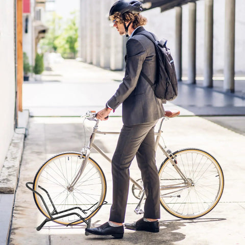 Commuter in suit parking bike in Two Pack Bike Floor Stand For Mountain And Road Bicycles, Fits 20 To 29 Inch Wheels, 23C To 4.0 Inch Wide Tires, Indoor Outdoor Bike Rack, Easy Push On Parking For Front Or Rear Wheel, Black.