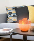 Himalayan Salt Lamp Bowl With Crystal Chunks, Dimmer Cord, And Classic Wood Base on coffee table in cozy living room