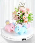 Tuanse 10 Inch Electric Motorized Rotating Turntable Cup Display Stand With Led Light showcasing plush unicorns and flowers on a white base.