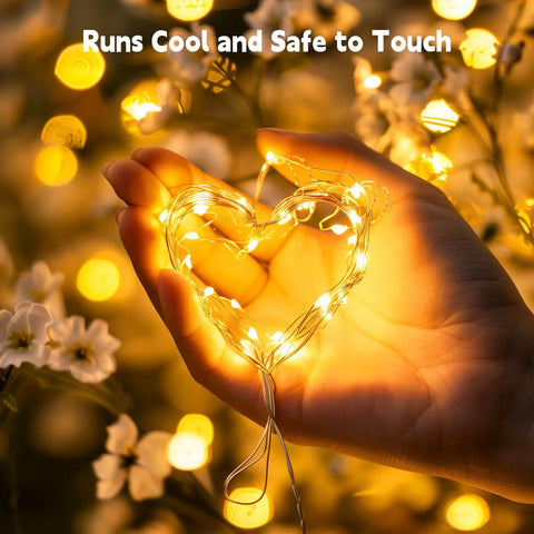 Warm White Plug In Fairy Lights 33Ft 100 LED Silver Wire Firefly String Lights With Adapter glowing in heart shape on hand