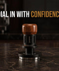 Close-up of 58mm espresso tamper with self leveling base, walnut handle on dark countertop, 'Dial in with Confidence' text.