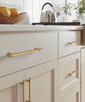 Champagne Bronze Traditional Cabinet Pull installed on kitchen cabinets, showing five and one sixteenth inch center to center mounting.