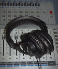 Closed Back Studio Mixing Headphones With 40mm Neodymium Drivers on a soundboard, showing padded headband and ear cushions.