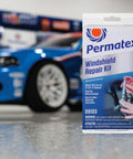Windshield Repair Kit For Chips And Cracks With Permanent Airtight Seal package in front of blue car in garage