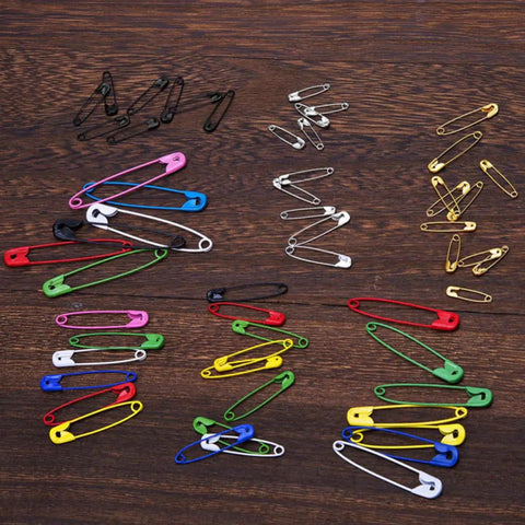 Kickass Assorted Steel Safety Pins Bulk Kit For Sewing Tailoring And Crafting in various colors on wooden background.