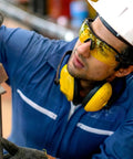 Hella Durable 12 Pack Safety Glasses For Men And Women Featuring Tinted Lenses With Top Tier Impact Resistance And Ansi Z87 Certification Perfect For Construction Sites And Diy Work, worn by a worker examining equipment.