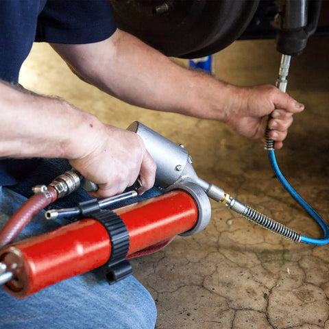 Man using 39 Inch Flexible Grease Gun Hose Kit With Spring Guard, 6 Inch Angled Tube, Standard Couplers And Sharp Type Nozzle One Eighth Inch NPT on vehicle