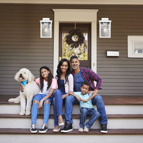 Family sitting on front porch with Auto On Outdoor Wall Lantern With Dusk To Dawn Sensor Seeded Glass Sconce mounted nearby