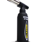 Big Shot Butane Torch GT8000 With Anti Flare Brass Frame Nozzle Attachable Tabletop Base Gas Flow Dial Piezo Ignition 2500 Degree Fahrenheit Flame Precise Tip For Searing Cooking Crafting And DIY Projects, angled on base