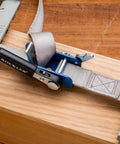 Workhorse Durable 1 Inch By 15 Inch Quick Grip Band Clamp securing a piece of wood with ratcheting handle for woodworking projects.