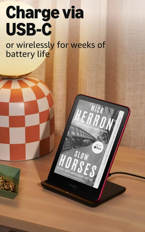 Kindle Paperwhite Signature Edition 7 Inch E Reader With 32GB Storage Featuring Auto Adjusting Front Light Wireless Charging And Sweet Long Battery Life In Sleek Metallic Black charging via USB-C on a stylish wooden table.